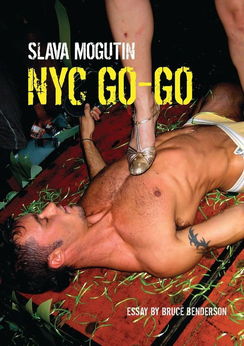 A shirtless man lying on a red surface with green leaves scattered around, with a ballet shoe on his chest. The text reads: 'Slava Mogutin NYC GO-GO' and 'Essay by Bruce Benderson.'