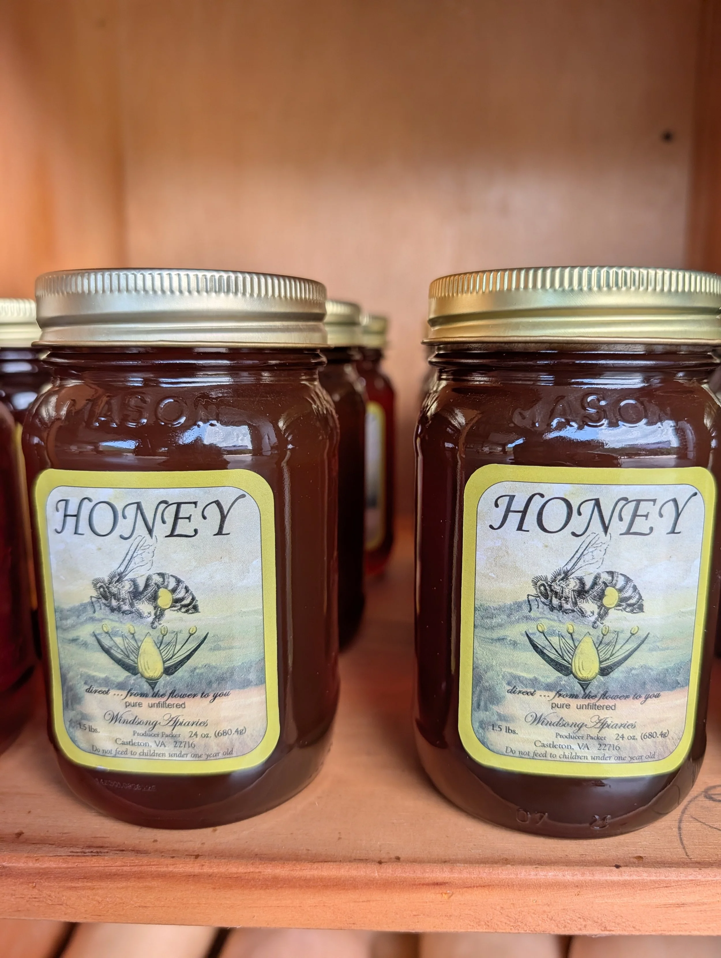Two jars of honey with metal lids on a wooden surface.