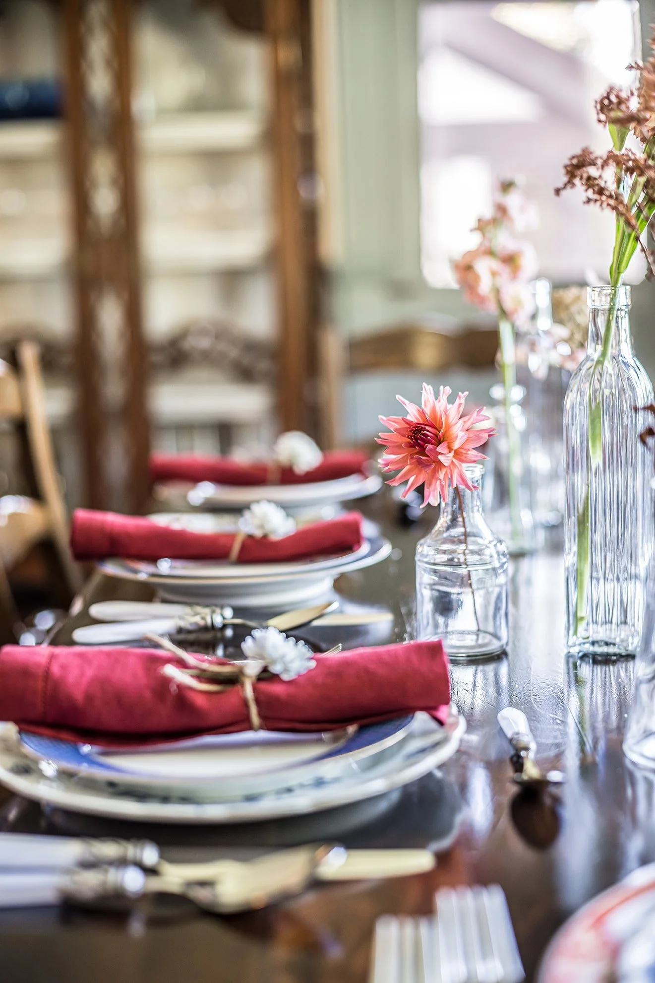 Beautiful traditional dining room set to entertain. Red linens with fresh flowers. Vintage Limoges dinnerware.  Rich wood tones.