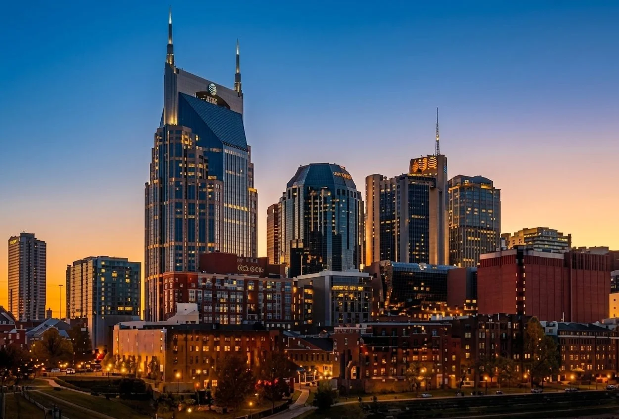 City skyline at sunset with tall skyscrapers illuminated.