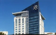 Modern high-rise building with glass facade and a large illuminated logo at the top.