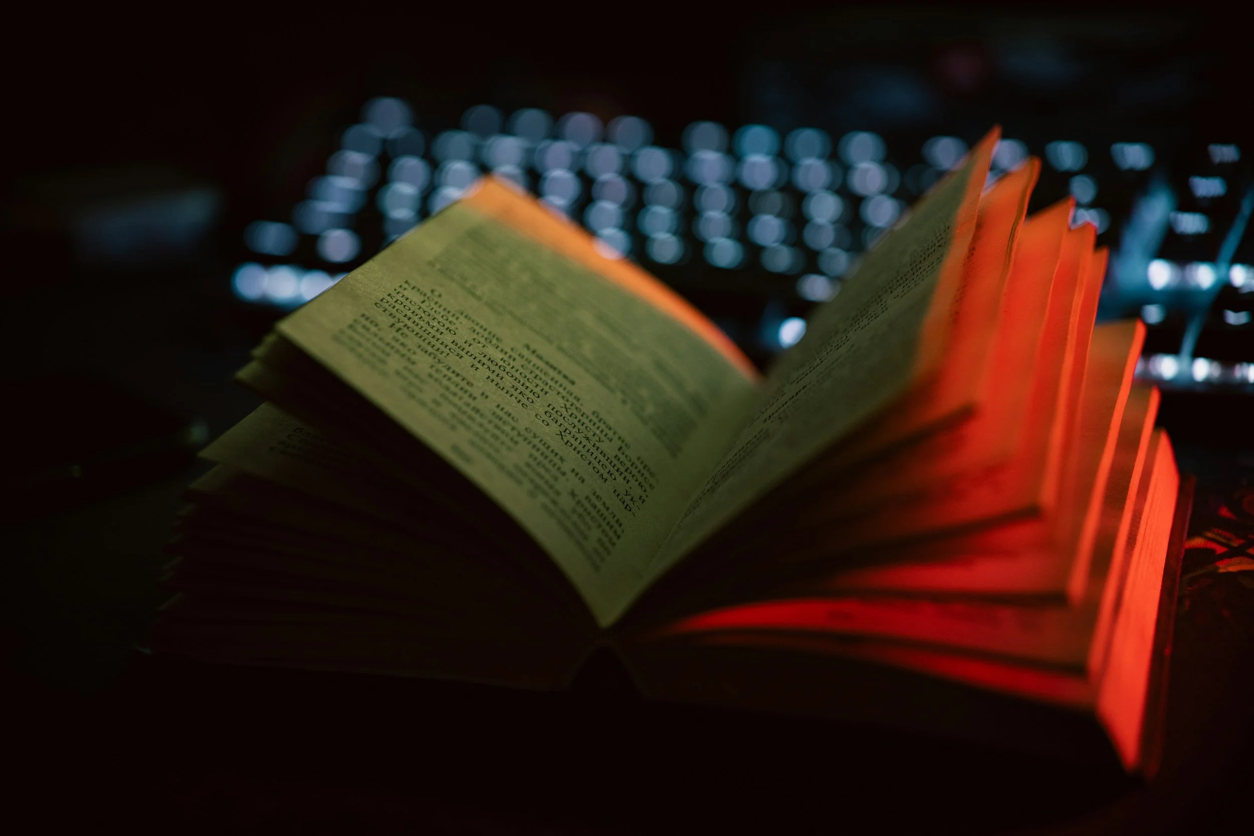 A lit book with orange pages against a dark background of bokeh lights.