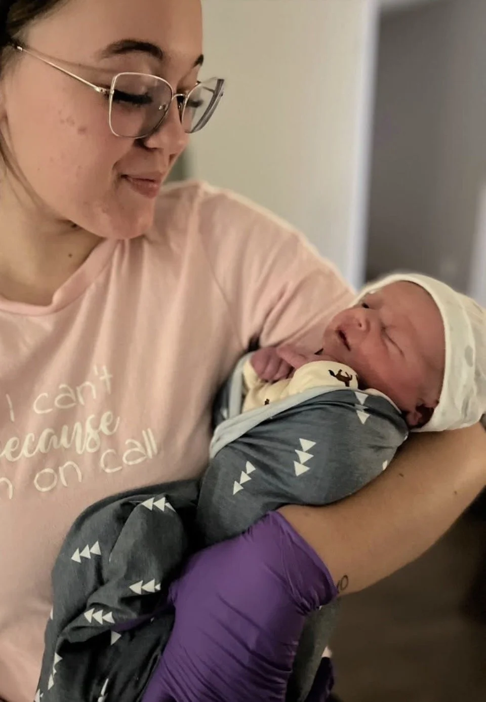 A woman holding a newborn baby inside a room.