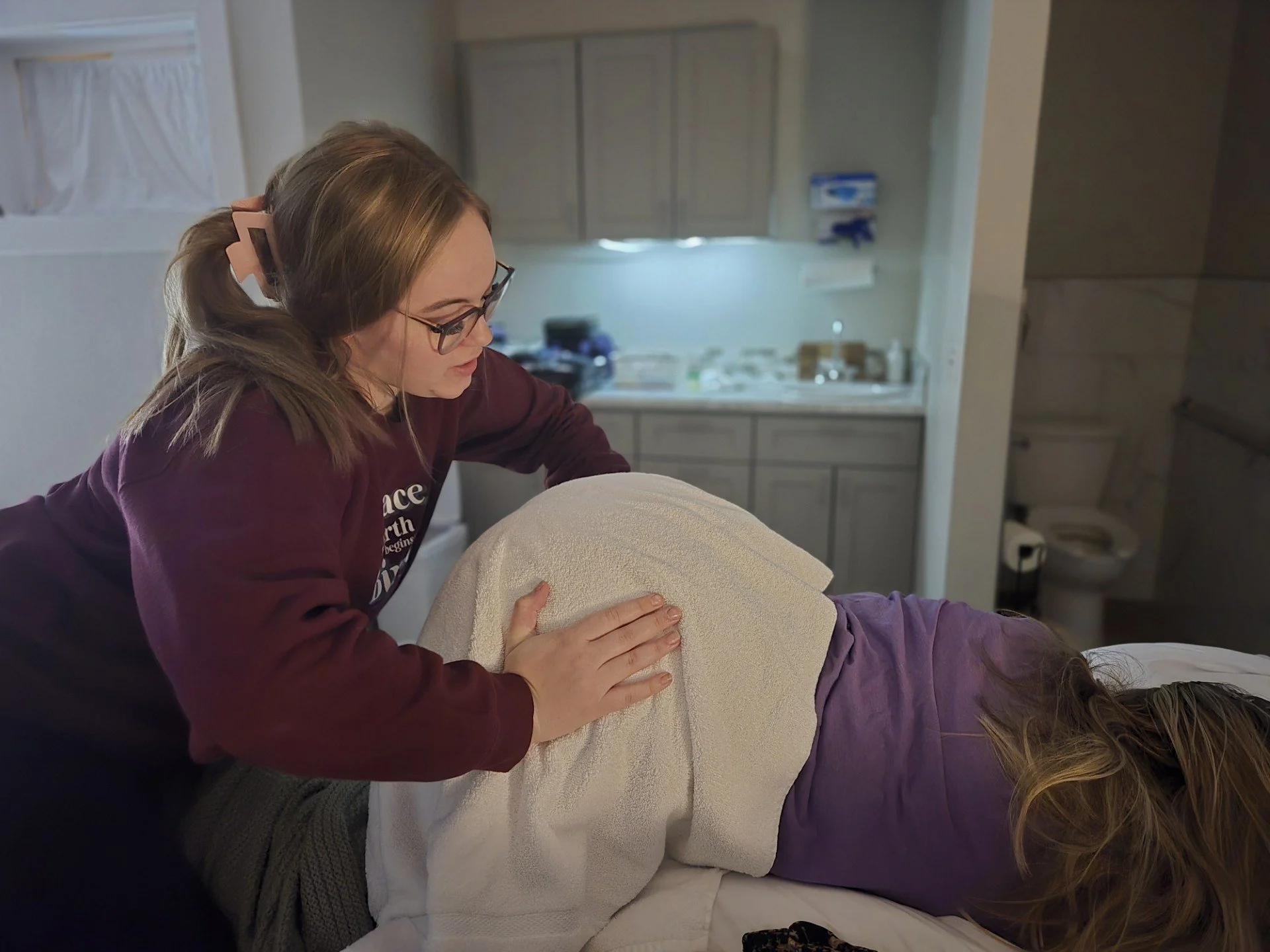A woman receiving a massage from a therapist in a therapy room.