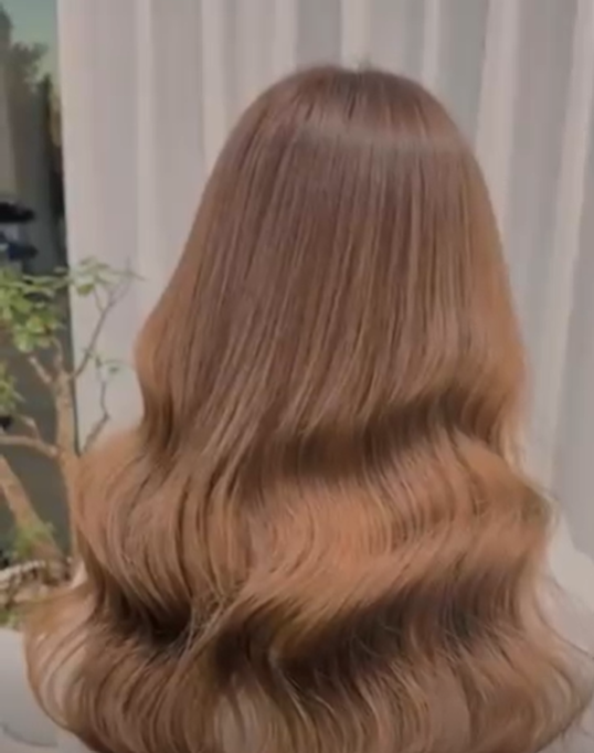 Back view of a person with long, wavy, light brown or blonde hair.
