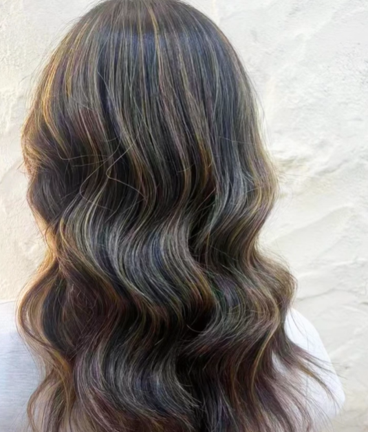 Back view of a woman's wavy hair with multi-color highlights
