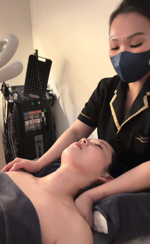 A woman receiving a facial treatment from a professional in a spa or clinic setting.