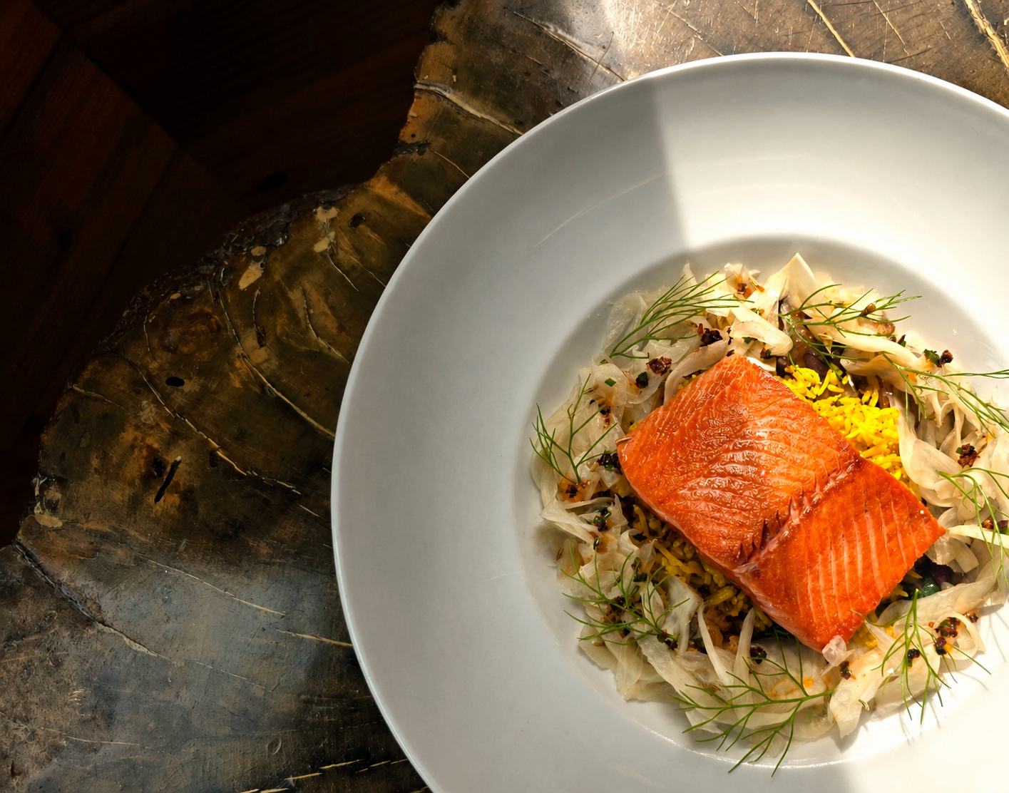 A plate of grilled salmon with cabbage slaw, garnished with dill, served on a white dish.