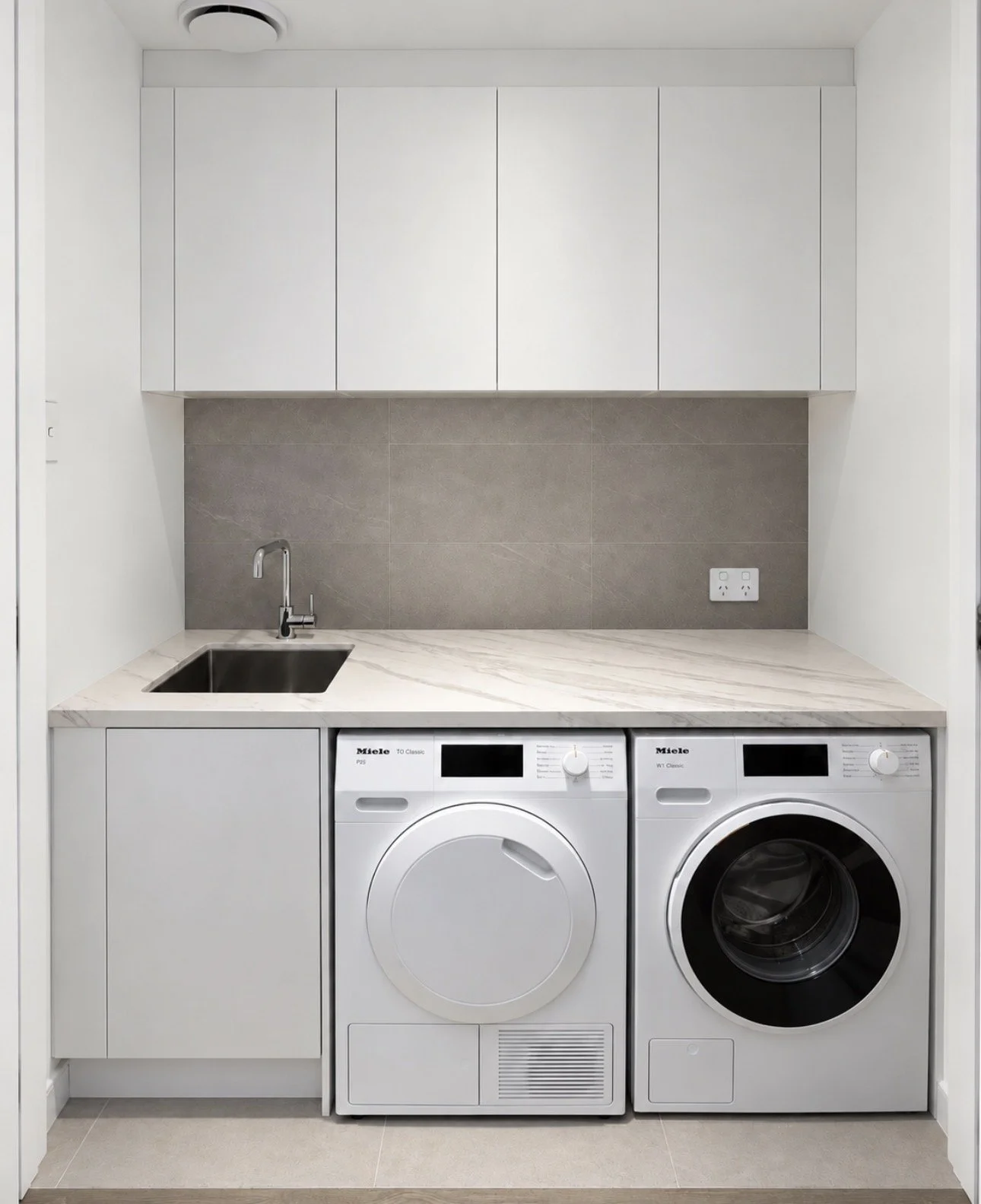 Finished Alphington laundry with side-by-side washer and dryer, sink and new benchtop.