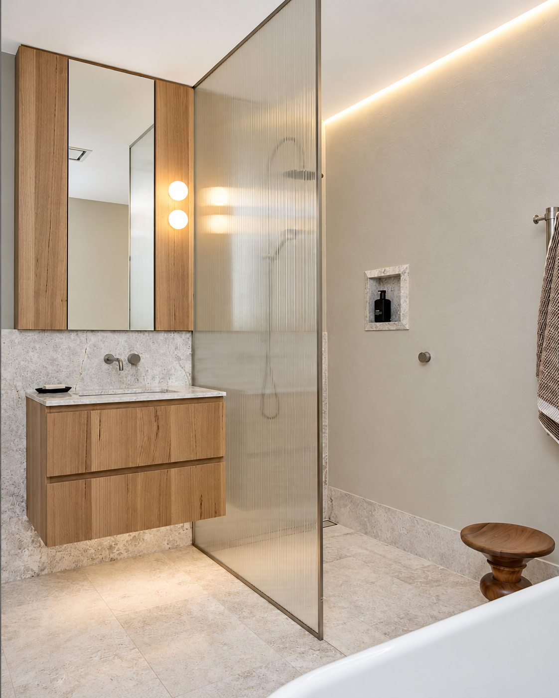 Modern bathroom with wooden vanity, marble countertop, mirror cabinets, frosted glass shower partition, small niche with soap dispenser, beige tiled floor, towel rack, and wooden stool.