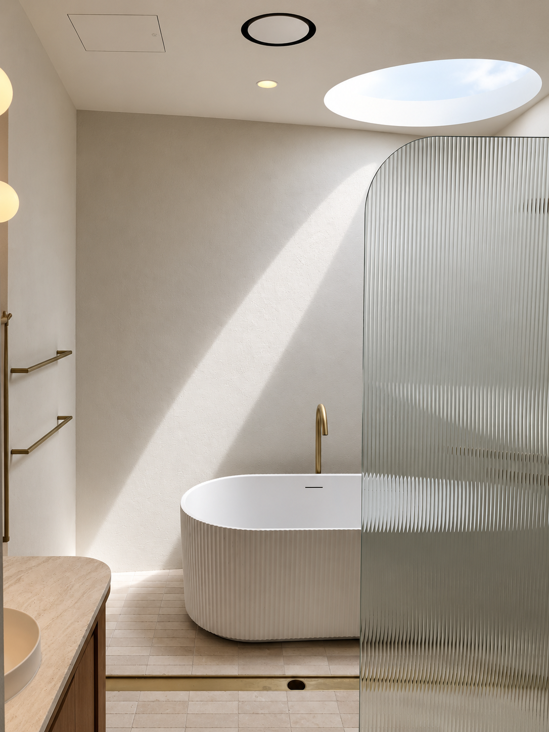 Modern bathroom with a round bathtub, gold faucet, frosted glass divider, and a skylight with natural light.