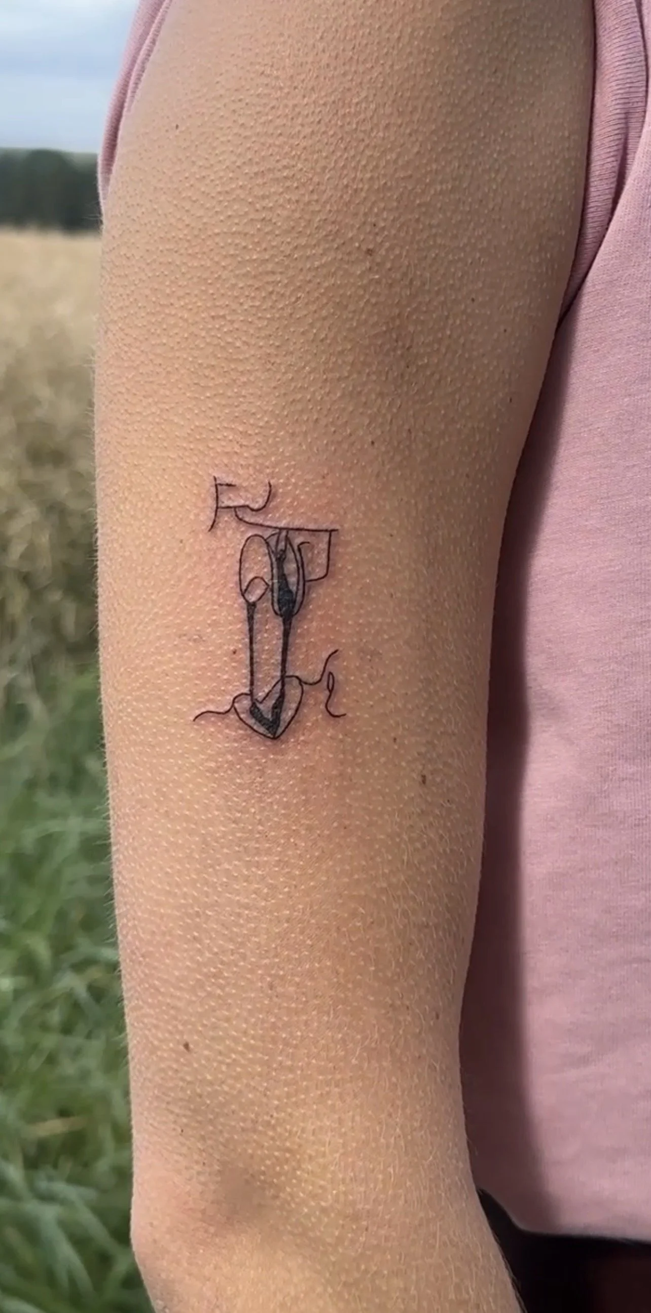 Dünner, schwarzer Straßenbahn-Tattoo auf dem Oberarm einer Person, bestehend aus Linien, Pfeilen und abstrakten Formen.