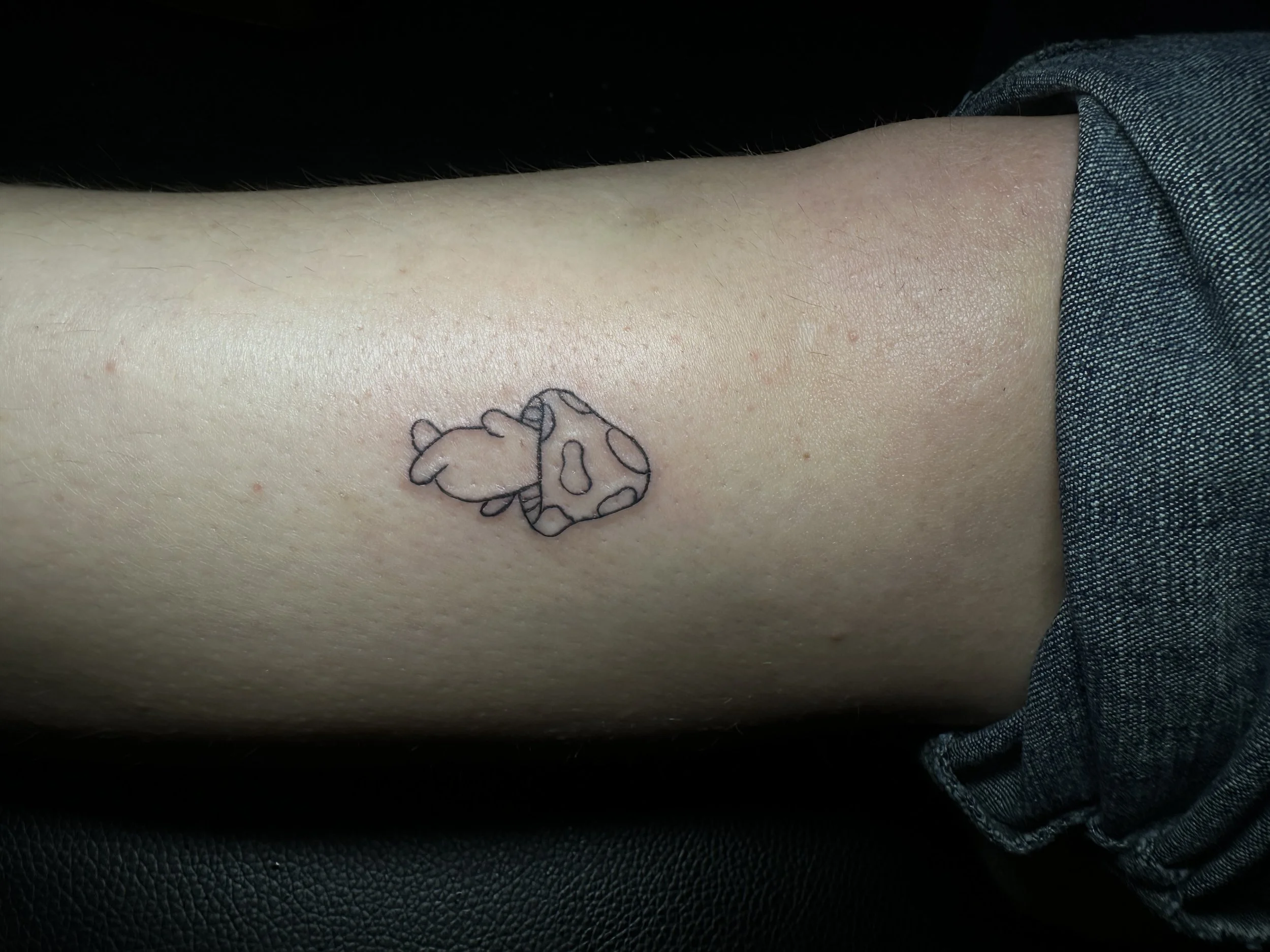 Nahaufnahme eines kleinen Tattoos eines Panda auf der Haut. Es ist nur eine einfache schwarze Konturzeichnung, in der Hautregion im oberen Bereich des Bildes.