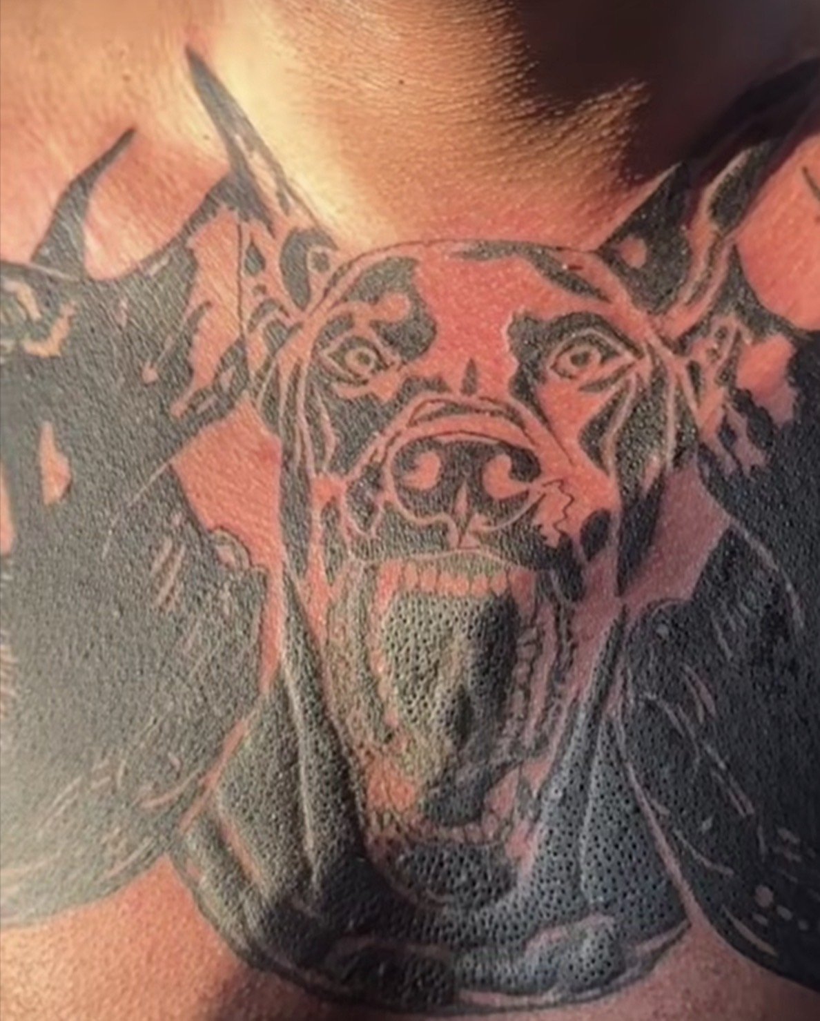 Tattoo eines Hundes auf der Schulter, schwarz-weißer Hund, realistischer Stil, Detailaufnahme.