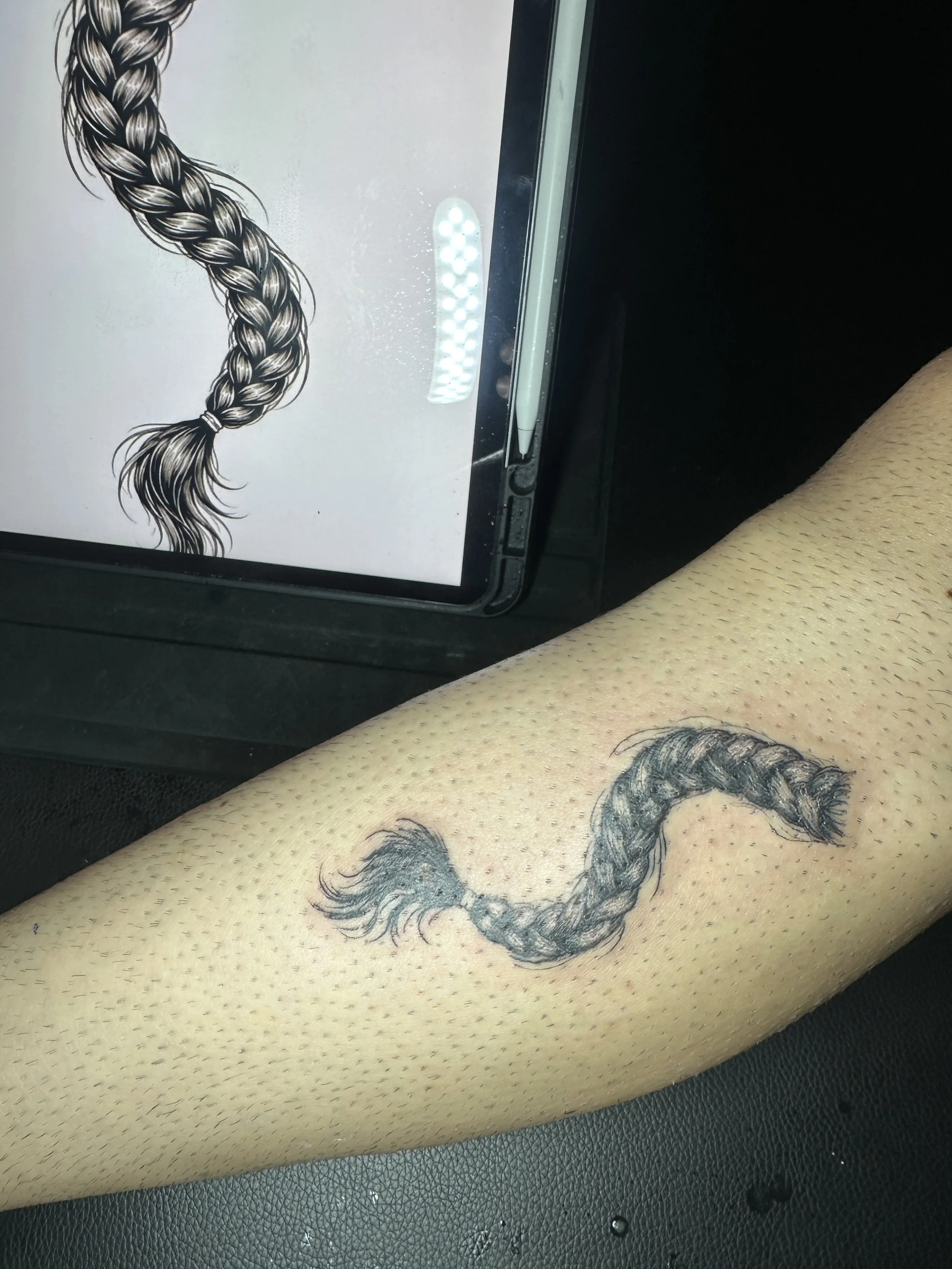 Tattoo eines schwarzen Drachens auf dem Oberschenkel einer Person.