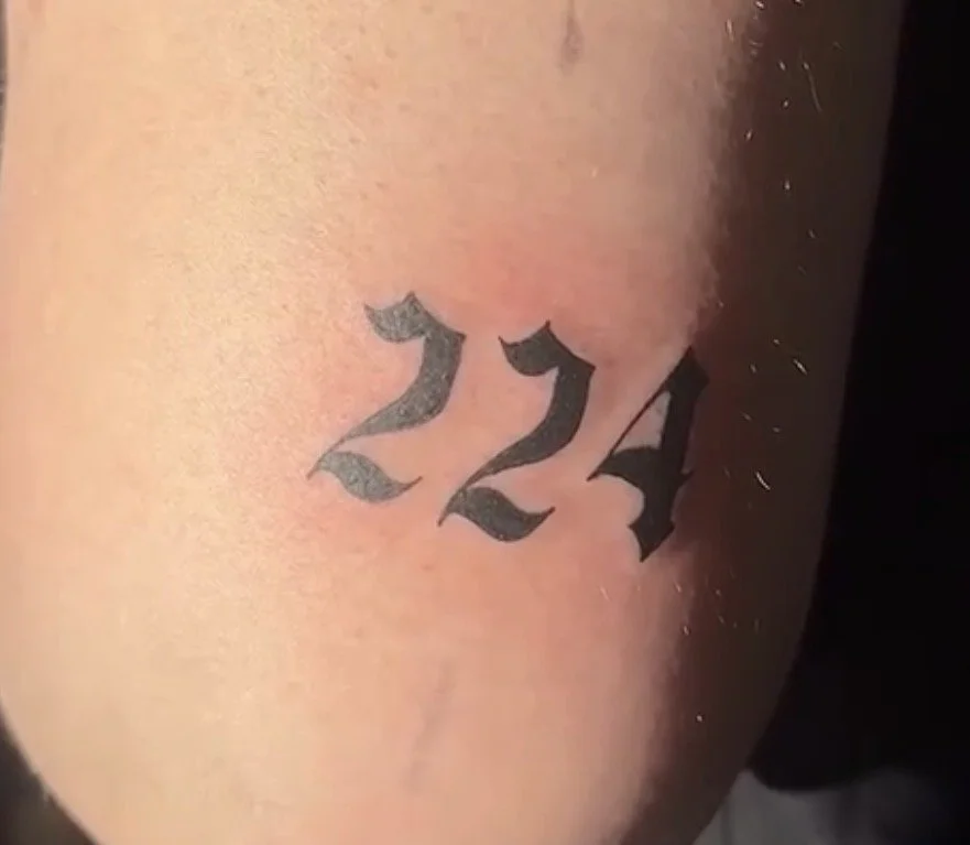 Tattoo mit der Zahl 224 in schwarzer Gotischer Schrift auf der Haut.