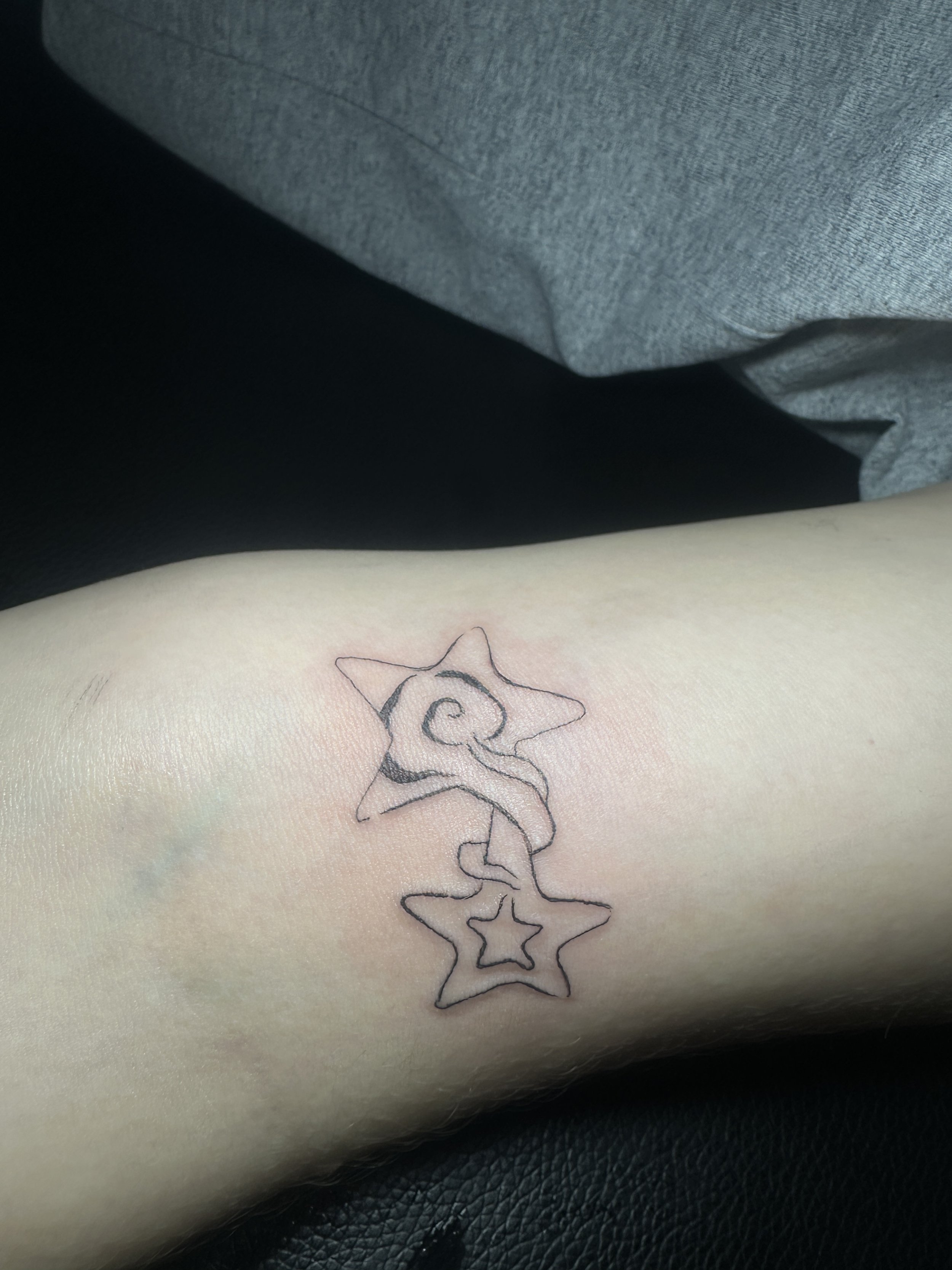 Tattoo von vier umrandeten Sternen in einer Linie auf heller Haut.