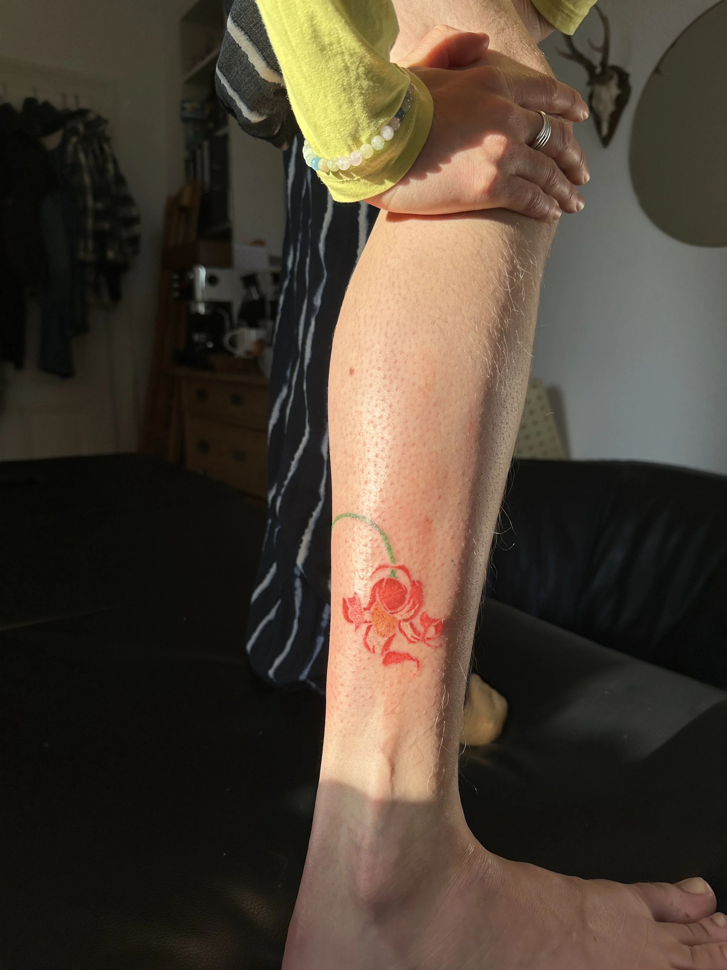 Eine Person hält ihr Bein in der Luft, auf dem Bein befindet sich ein Tattoo eines Rotkehlchens.
