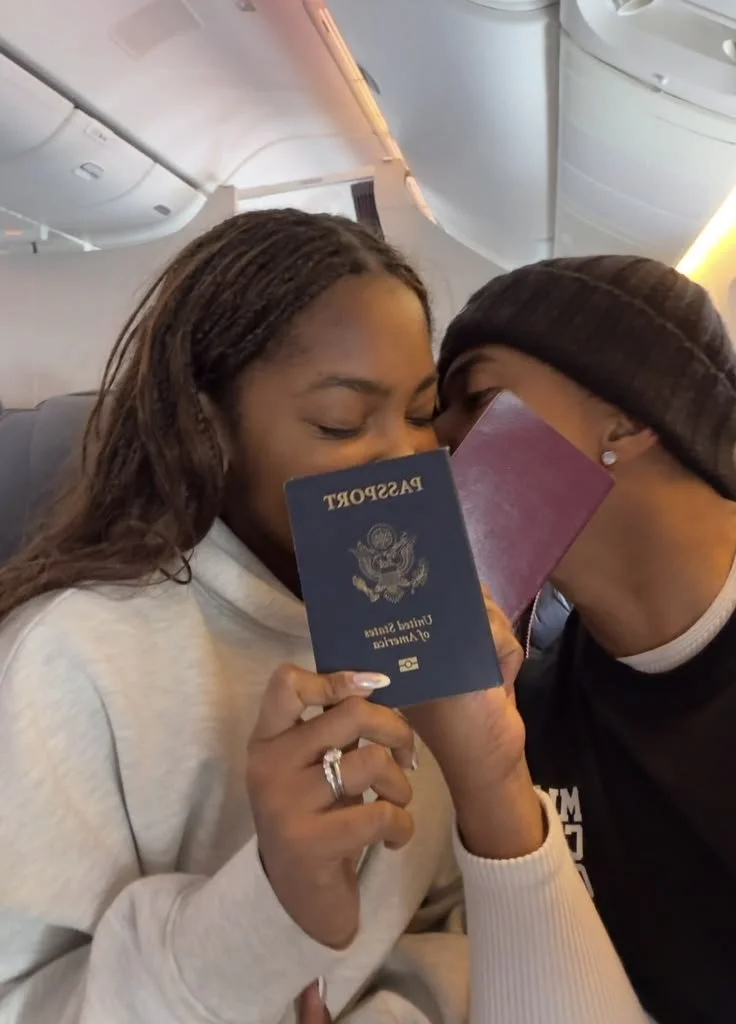 A woman and a man on an airplane sharing a close moment, with the woman holding a United States passport and an American airline boarding pass.