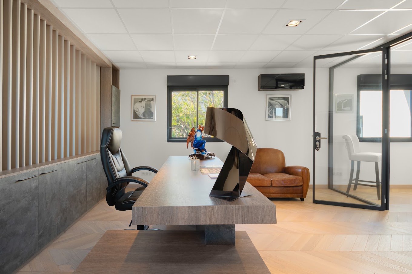 Aménagement d’un espace de bureaux contemporain avec mobilier en bois et grandes ouvertures vitrées.