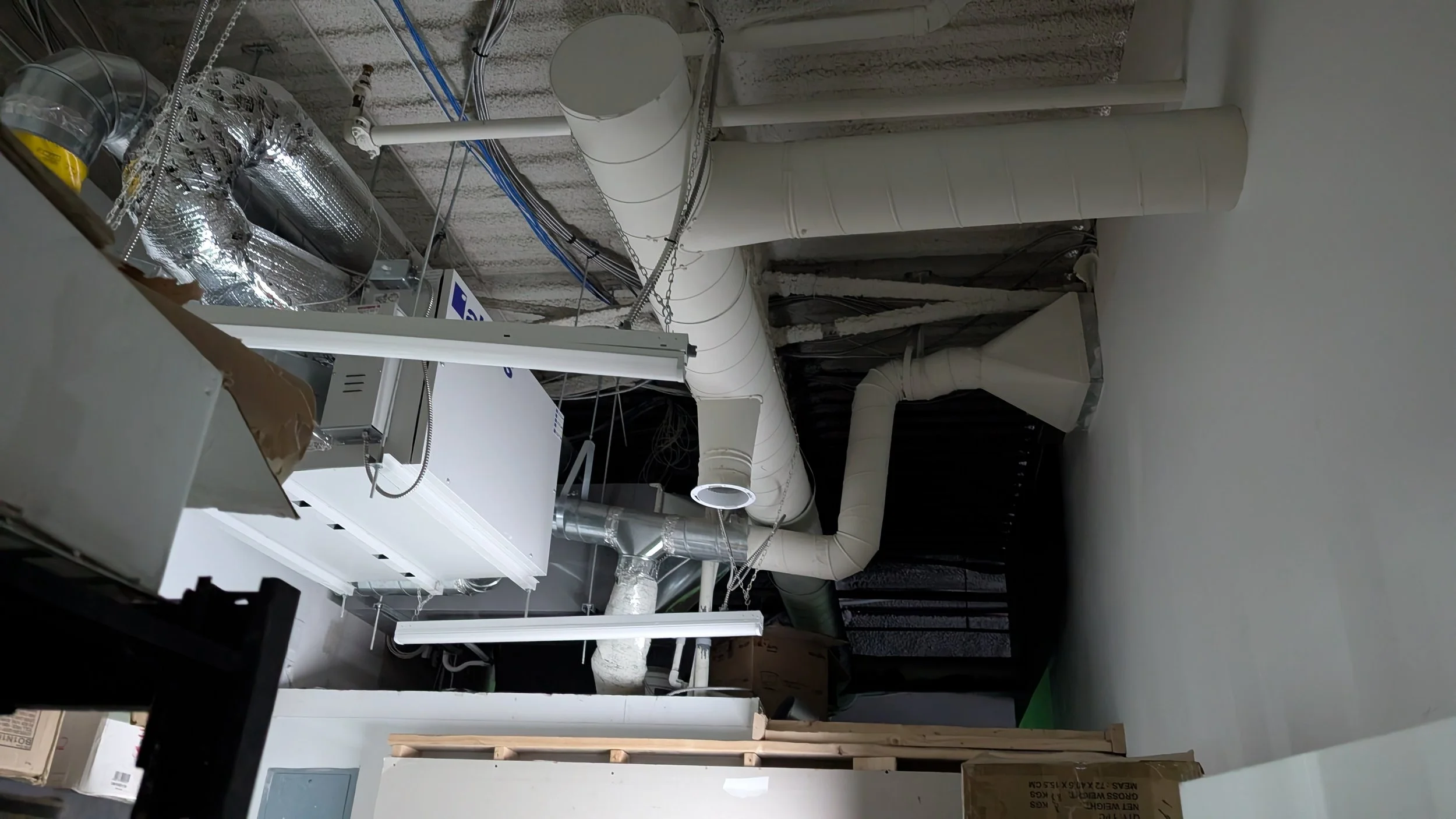 Ceiling with ducts, pipes, and electrical wiring in an unfinished basement or utility area.