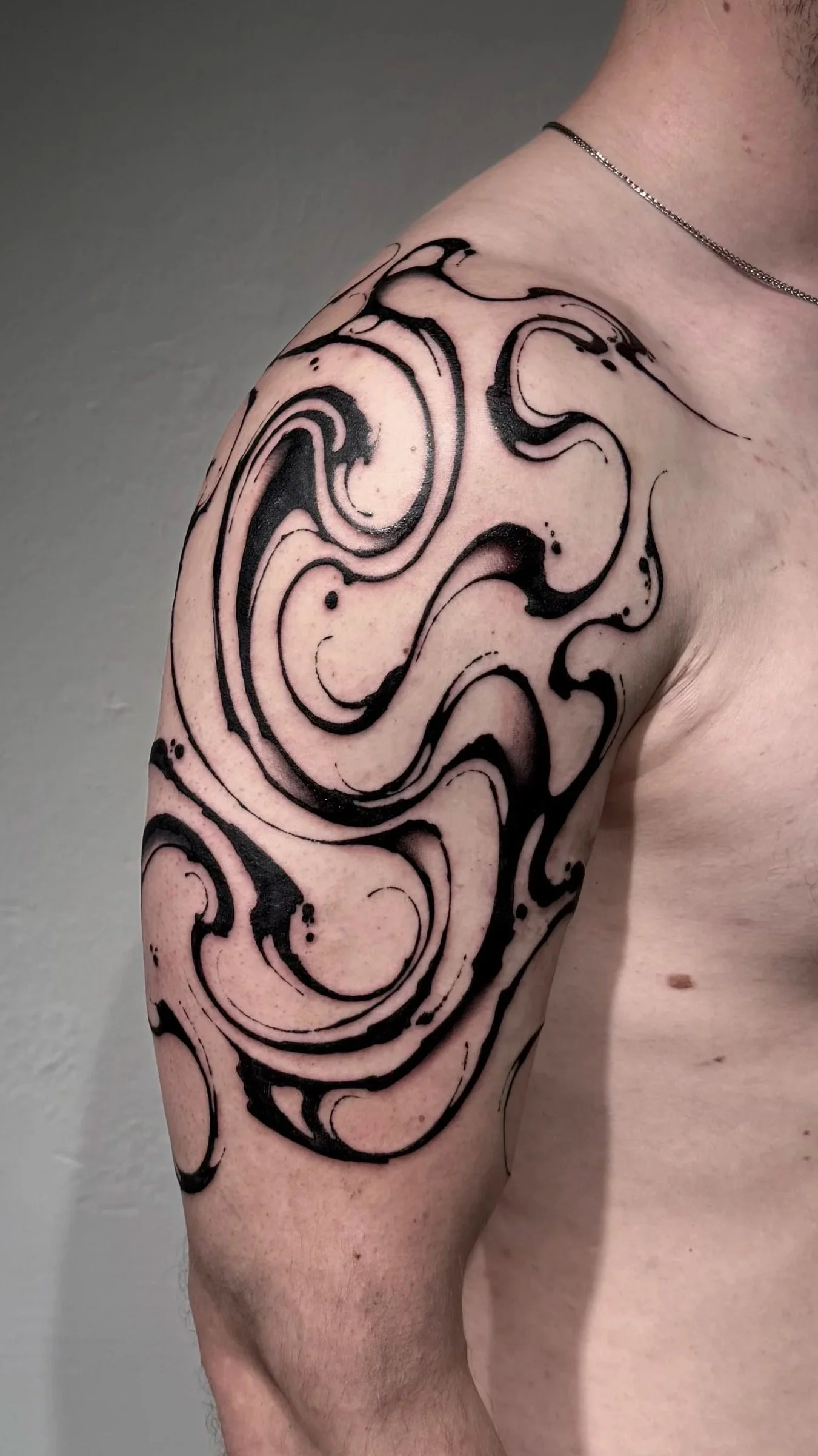 Schwarze abstrakte Tattoos auf der Schulter und Arm einer Person