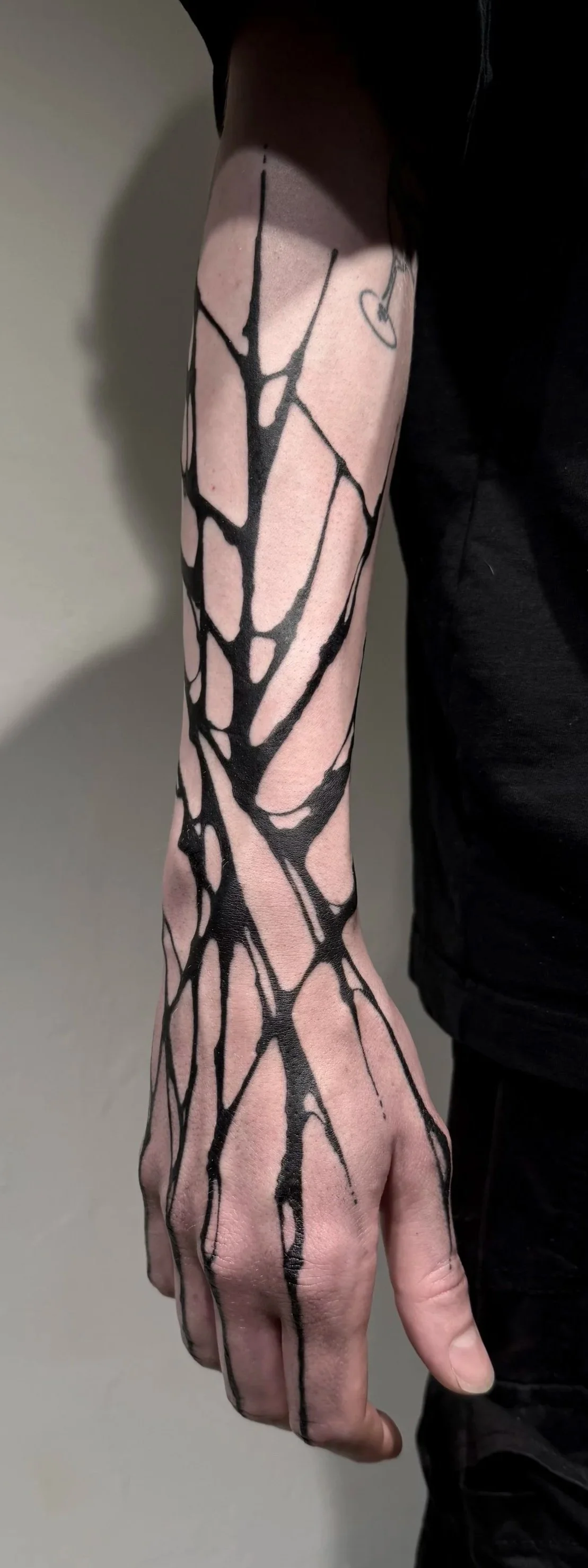 Schwarzes, abstraktes Baummotiv-Tattoo am Arm, schwarz auf Haut, nahaufnahme.