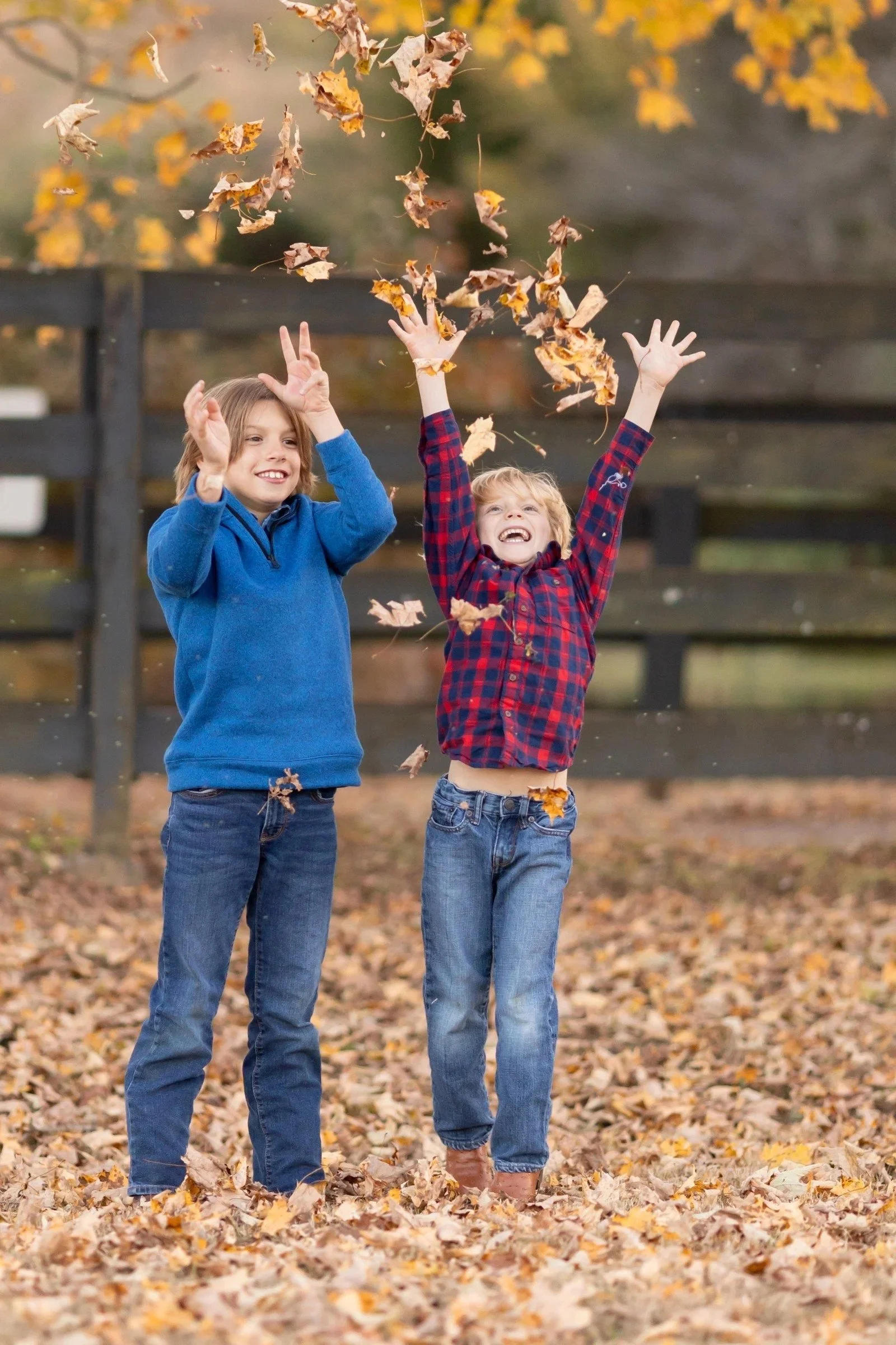 Two boys tossing fall leaves in the air