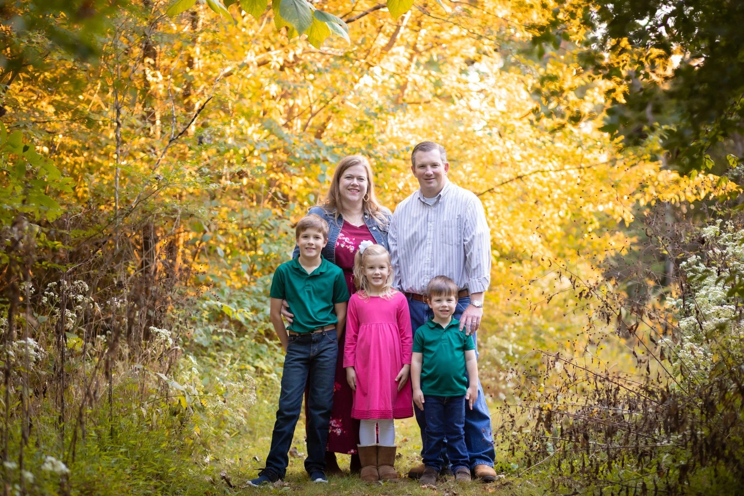 Family of five surrounded by bright yellow fall trees at Aspen Grove Park in Franklin, TN
