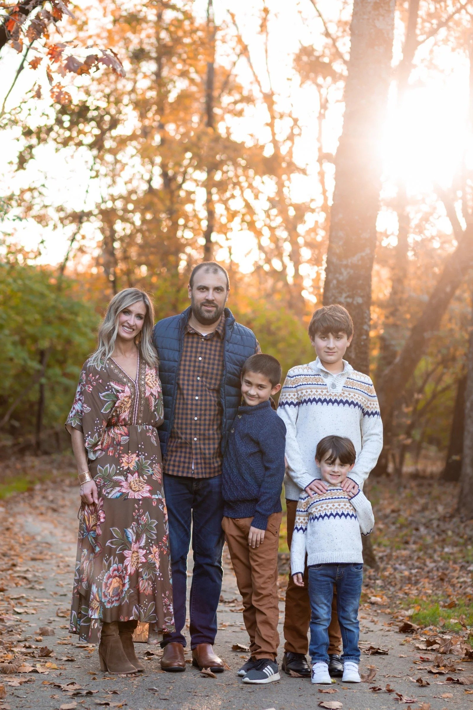 Family of five on a sunlit fall path at golden hour