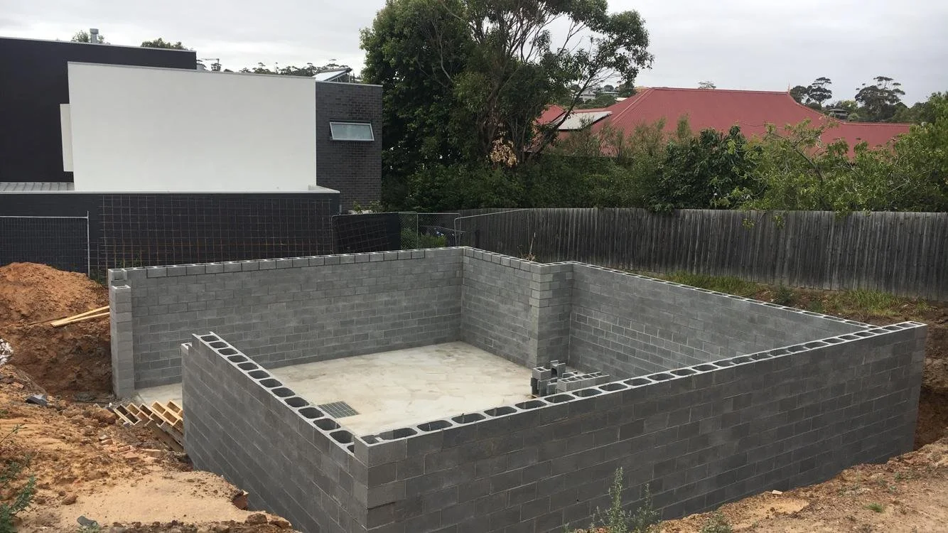 Grey blockwork courtyard walls framing a fresh concrete slab.