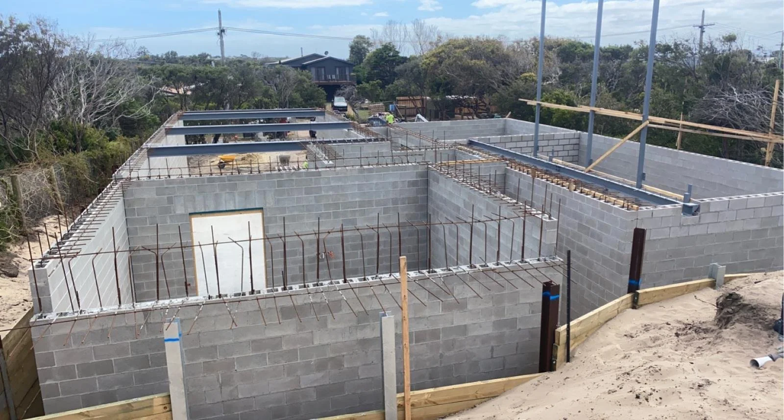 Structural grey blockwork walls rising on site during construction.