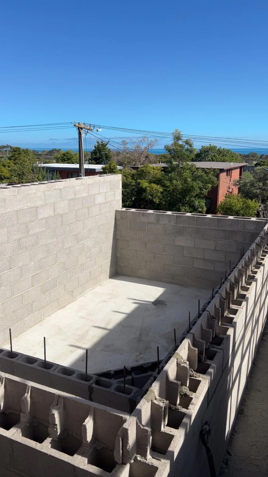Pale grey block retaining wall finished beside a concrete patio.