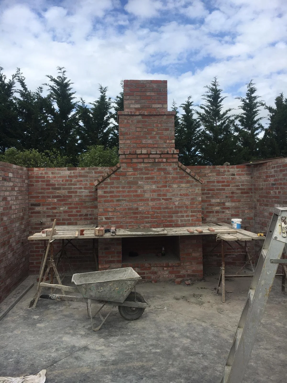 A brick outdoor fireplace and chimney taking shape, course by course.