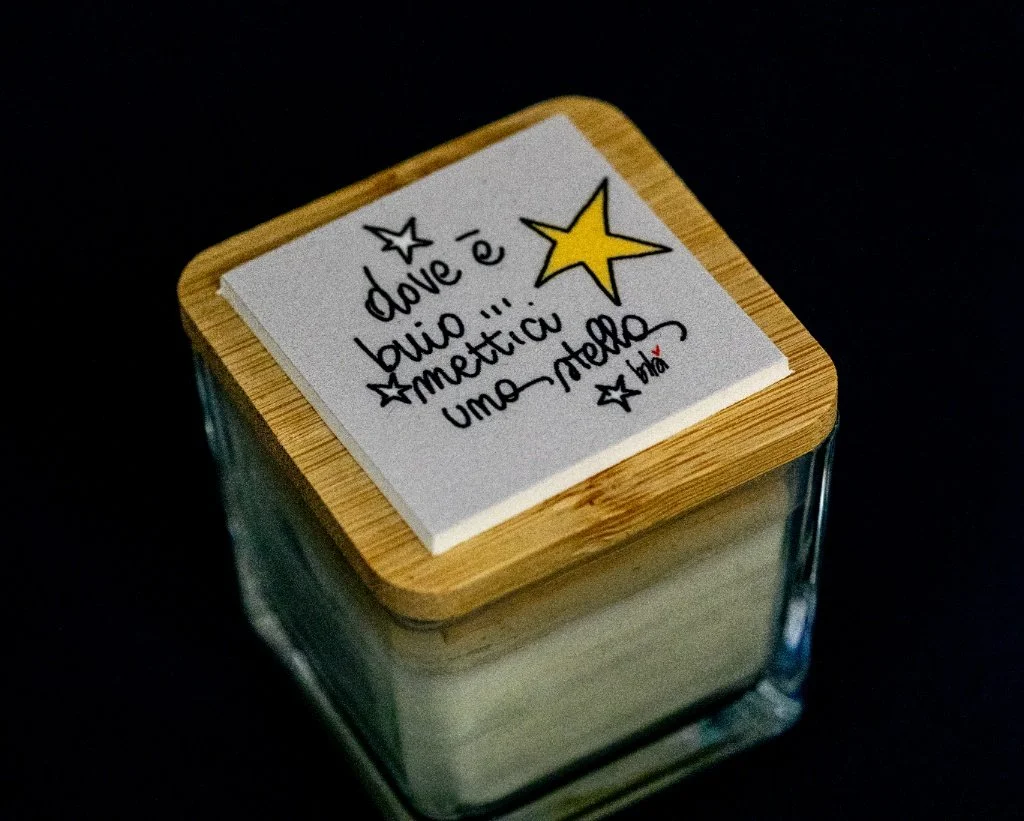 Vaschetta di vetro con coperchio di legno e un foglietto di carta con disegni di stelle e testo in italiano scritto a mano.