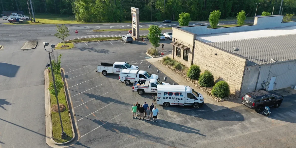 A parking lot with service trucks and five people standing together.