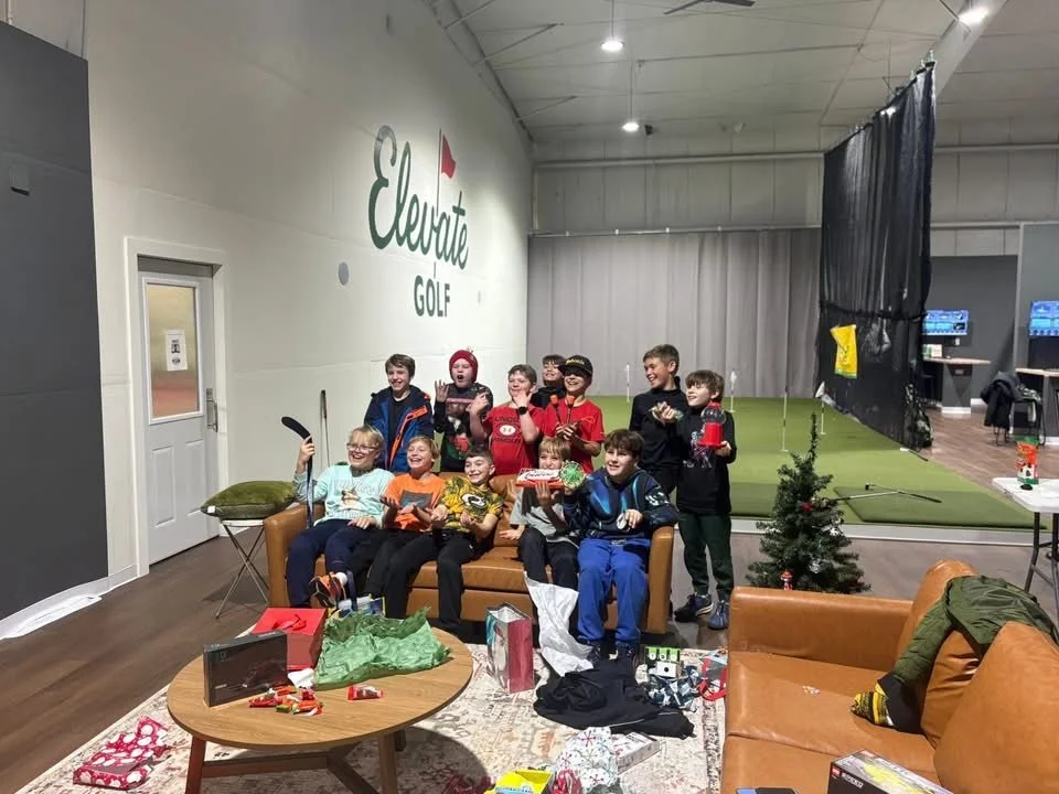 A group celebrates together beside Elevate Golf’s indoor putting green.