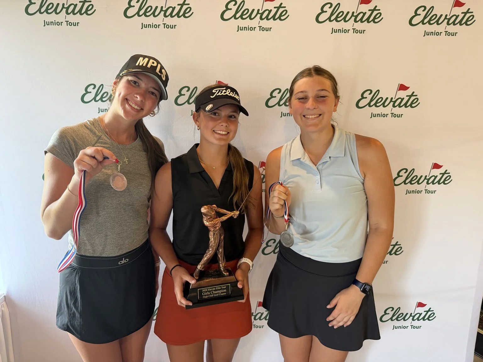 Elite Tour golfers celebrate with a championship trophy after competition.