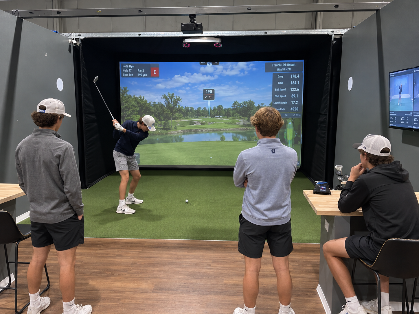 Junior golfers practice together in an Elevate Golf simulator bay.