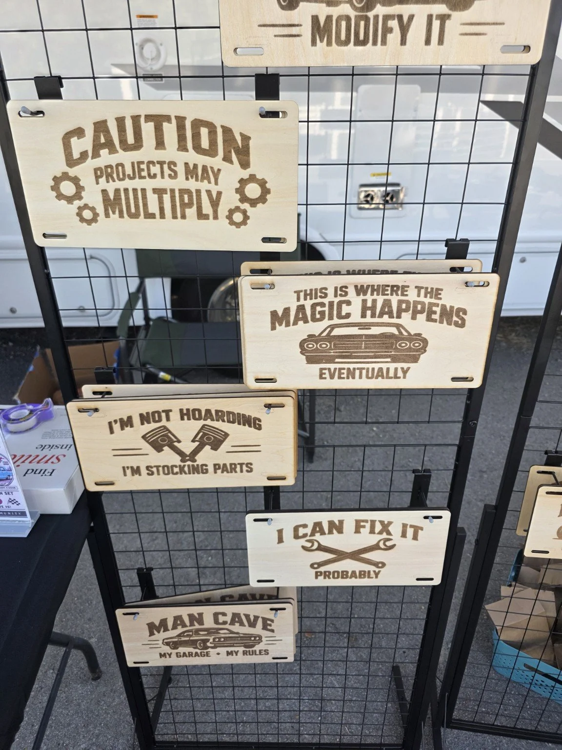 Engraved garage signs at the Curators Classics swap-meet display.