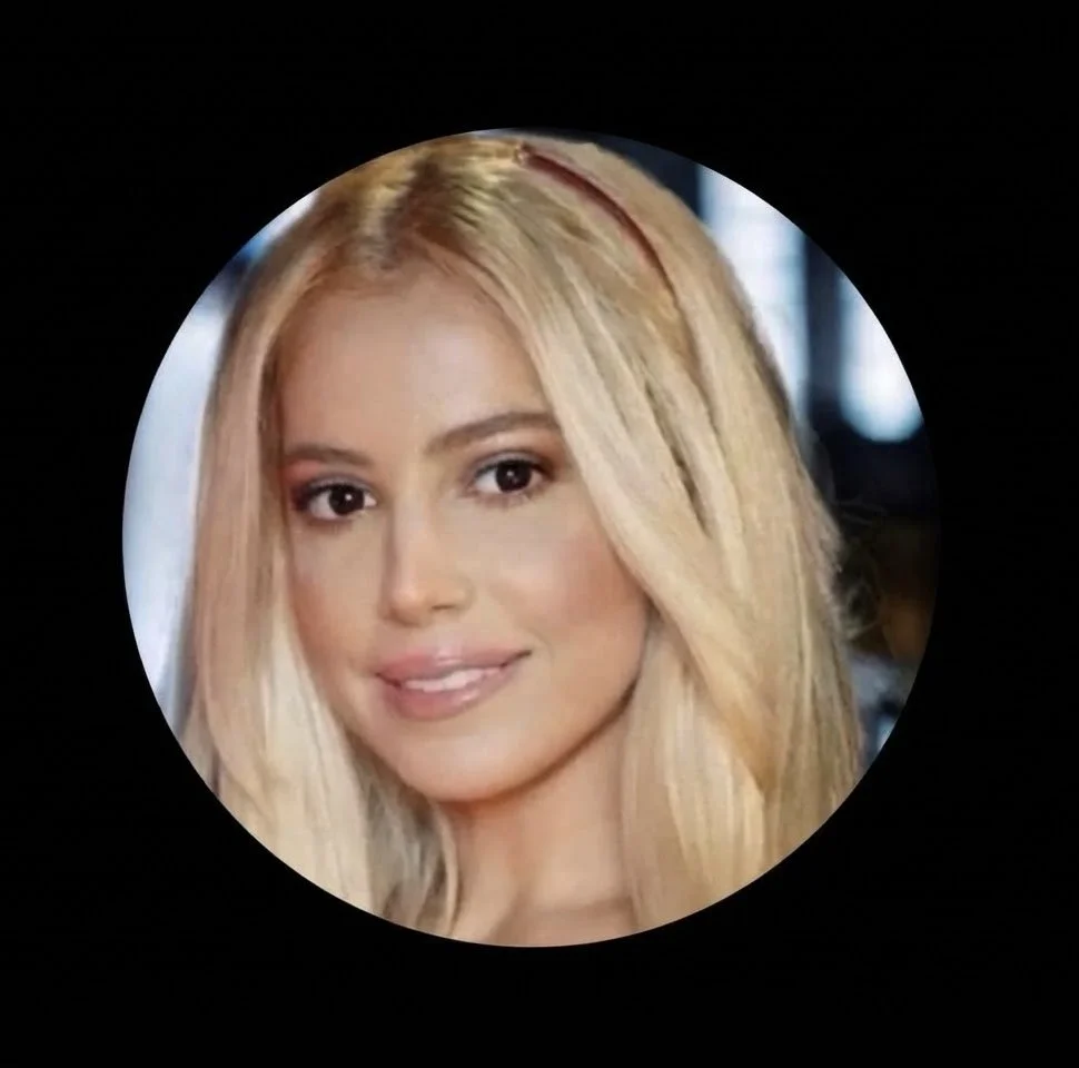 A woman with long blonde hair, light makeup, and a pink headband smiles at the camera.