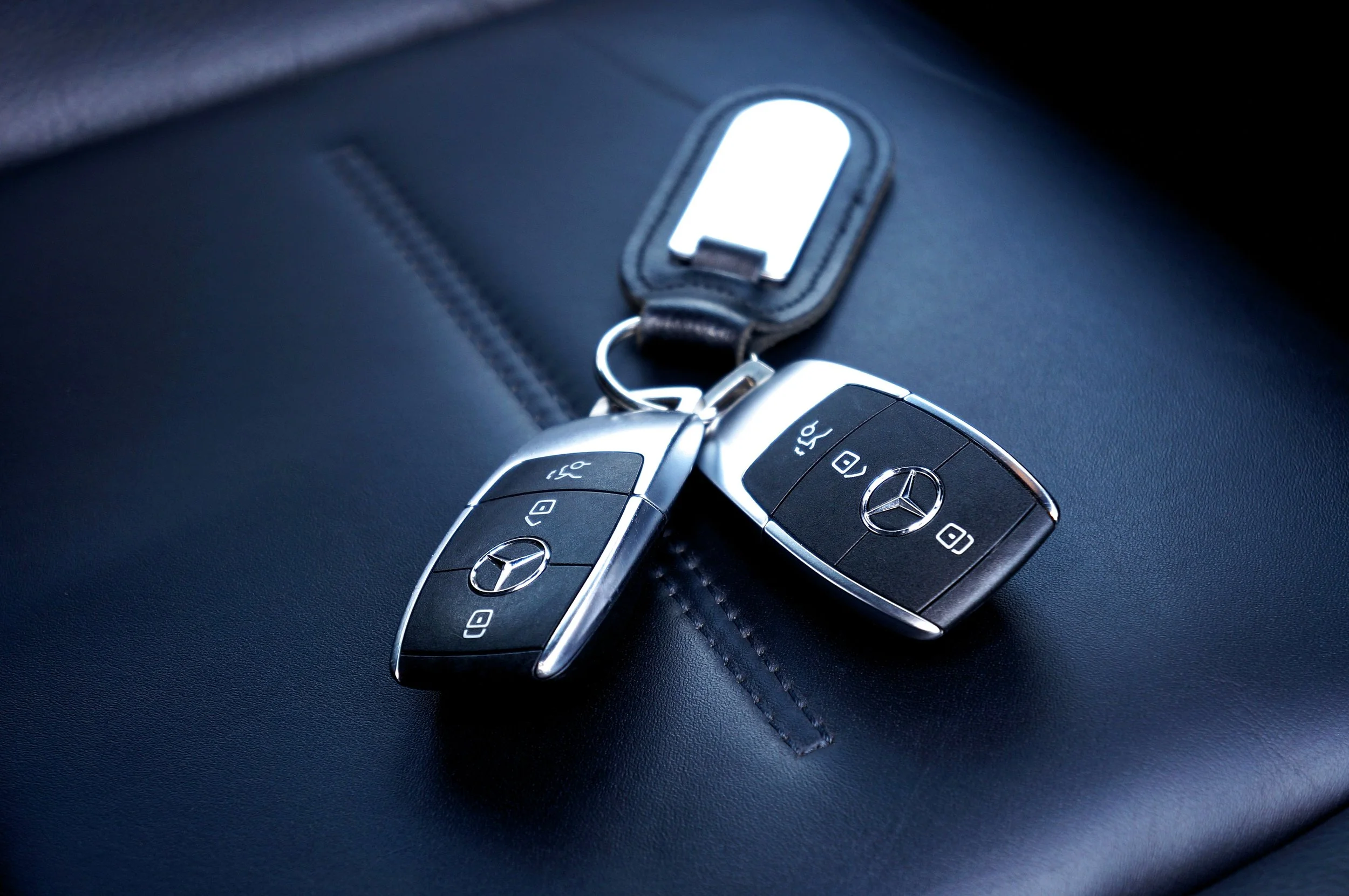 Close-up of a Mercedes-Benz key fob resting on a car seat.
