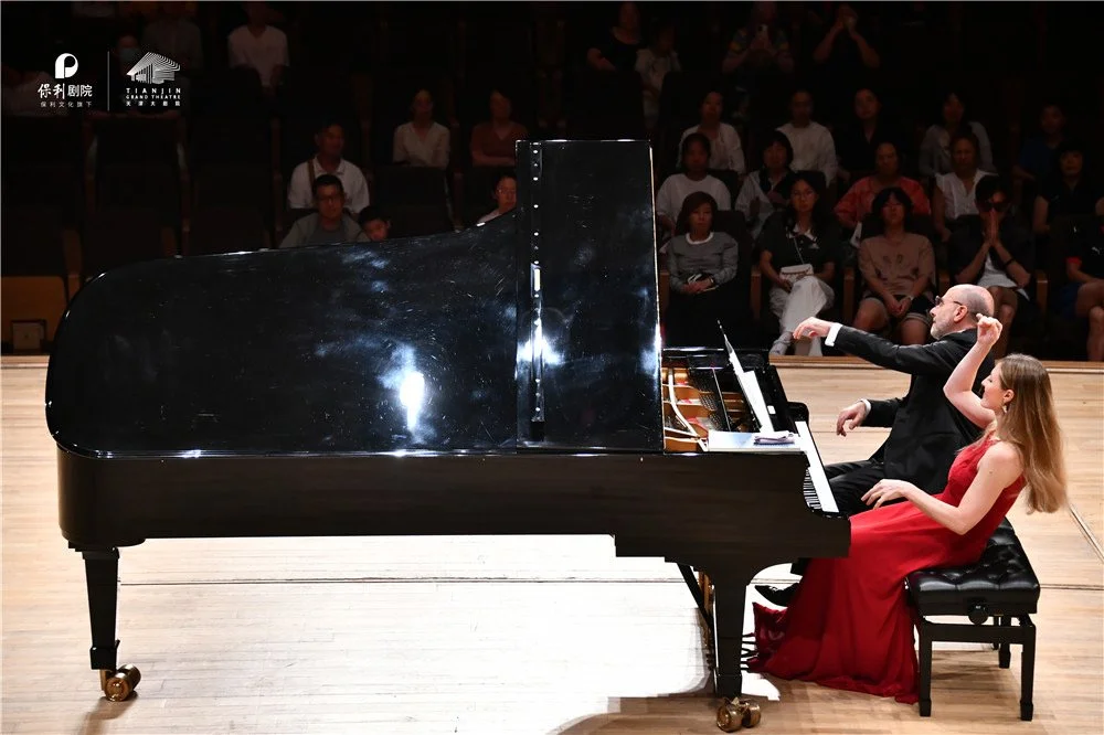     Sara Costa and Fabiano Casanova performing piano four hands before a concert audience.