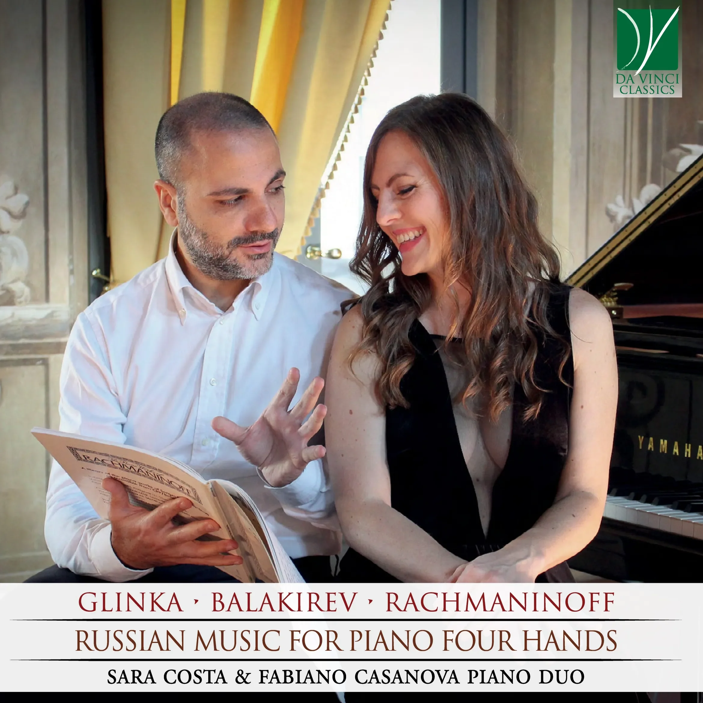 Sara Costa and Fabiano Casanova looking through a music score together beside a grand piano.