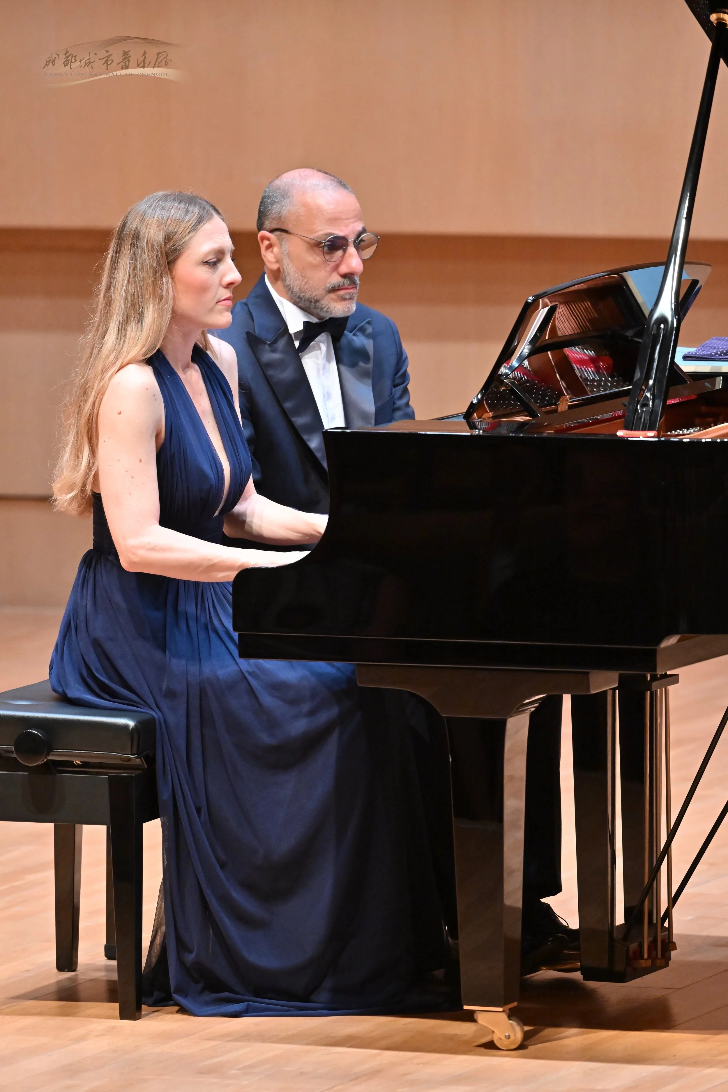     Costa & Casanova Piano Duo performing together at the piano on stage.
