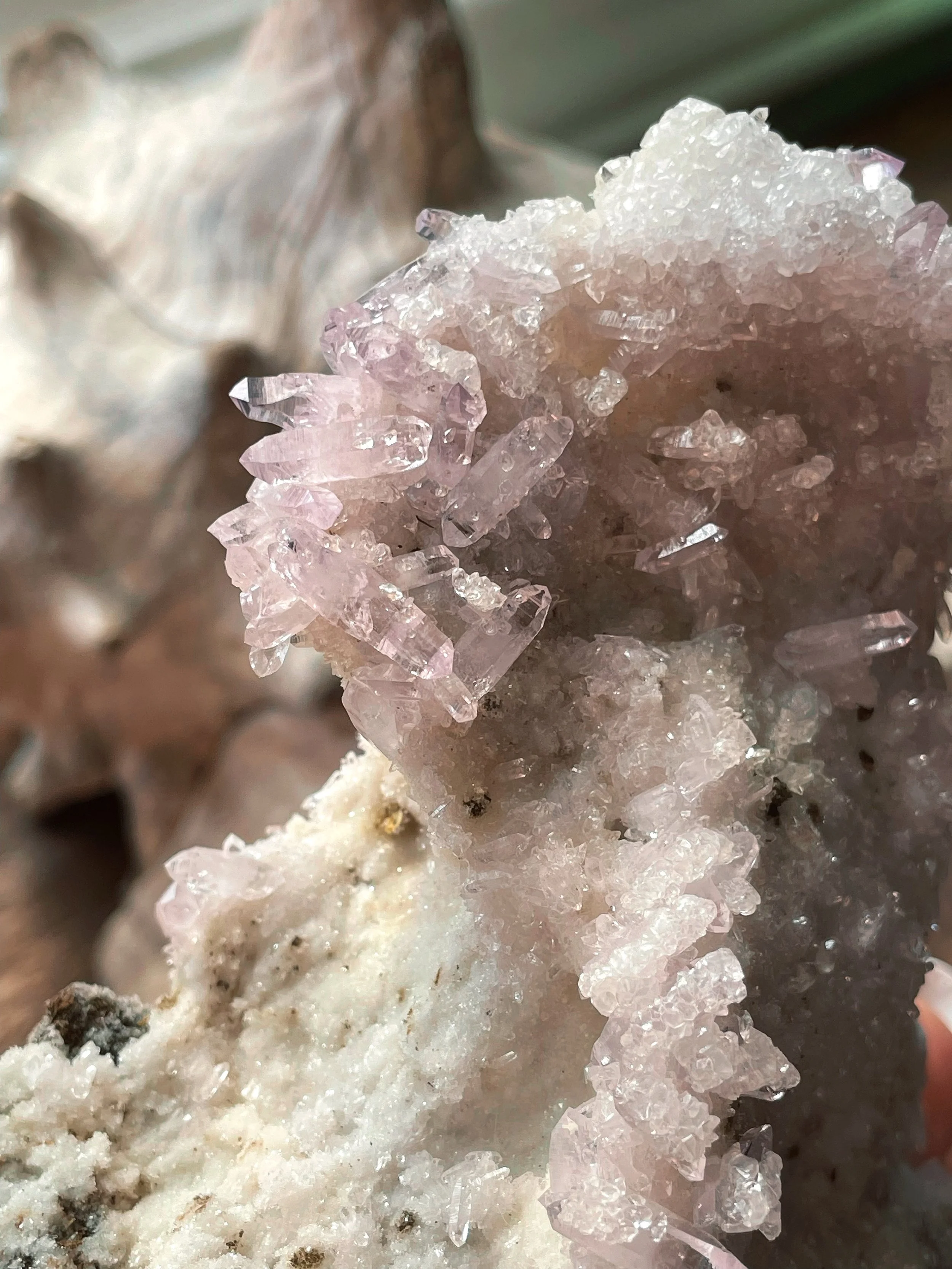 Close-up of pink and clear crystalline mineral formation on white rock surface.