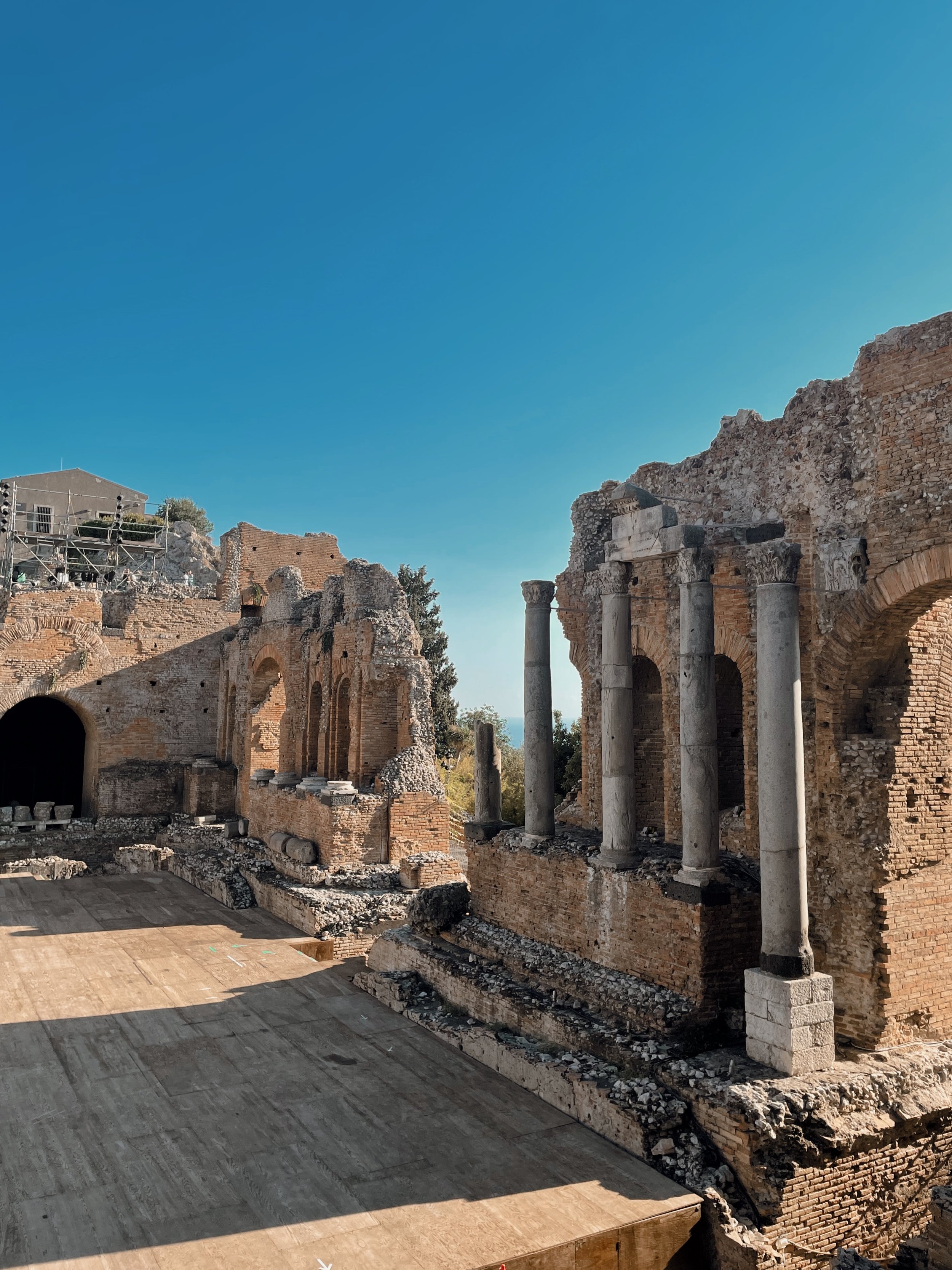 Ancient ruins with stone and brick structures, columns, and arches, under a clear blue sky.