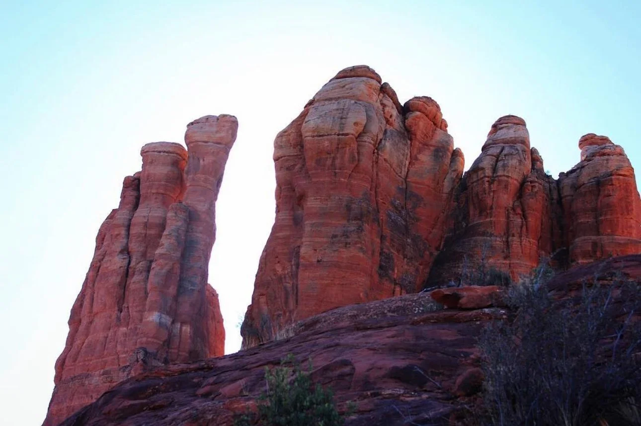 Red rock formations in a desert landscape with a clear sky in the background.