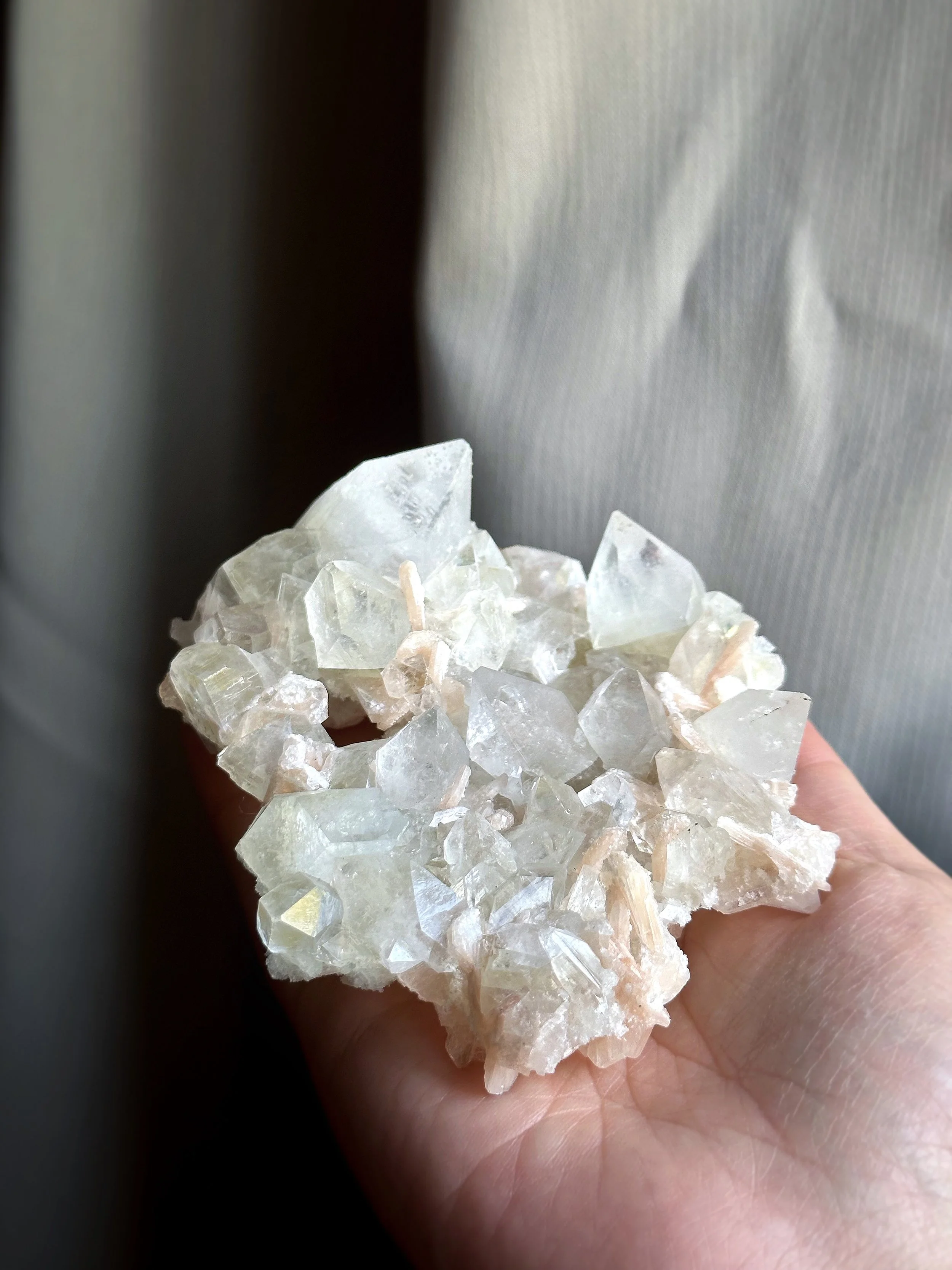 A person holding a cluster of translucent, irregularly shaped crystals or minerals in their hand.