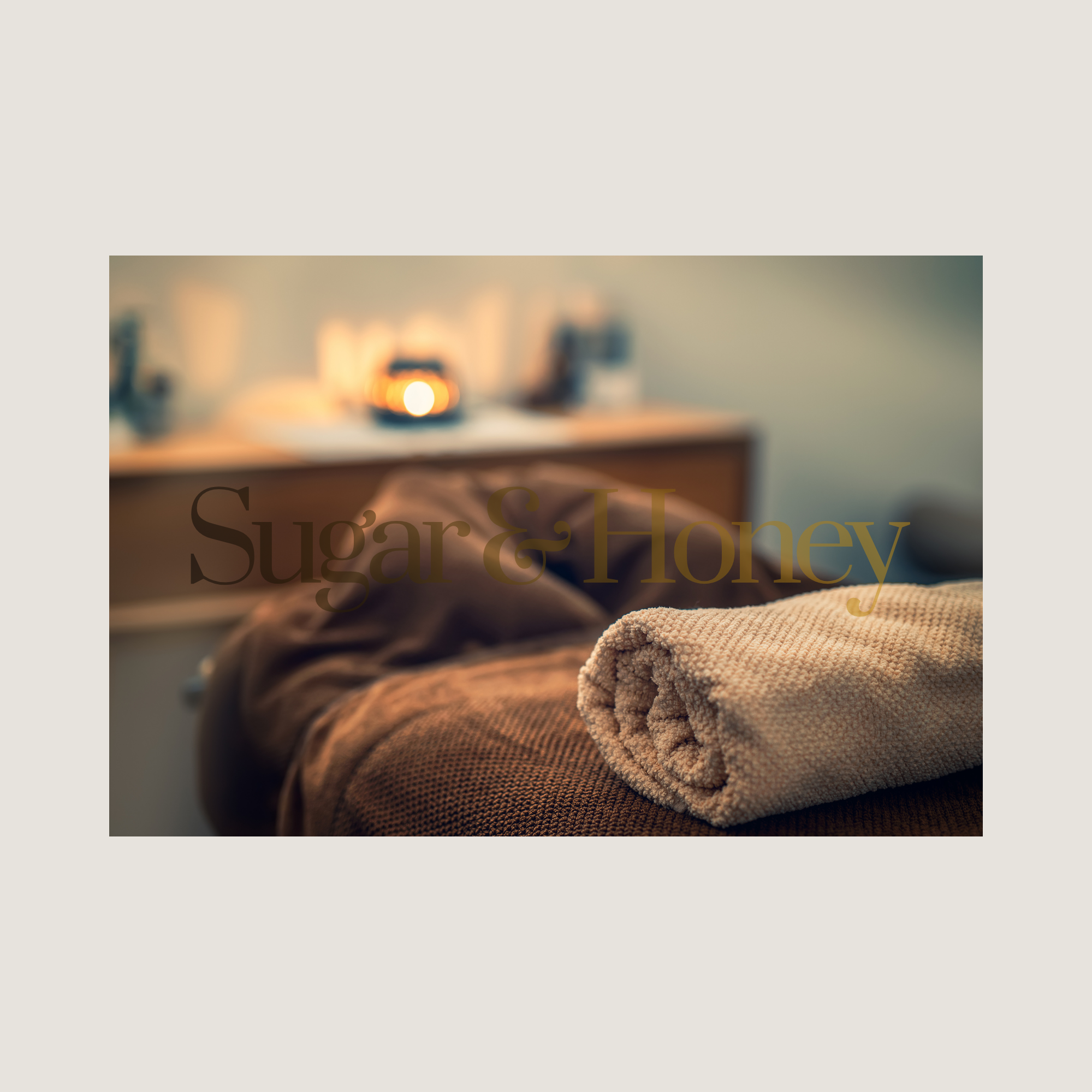 Rolled beige towel on brown textured surface with blurred candles and decorative items in background.